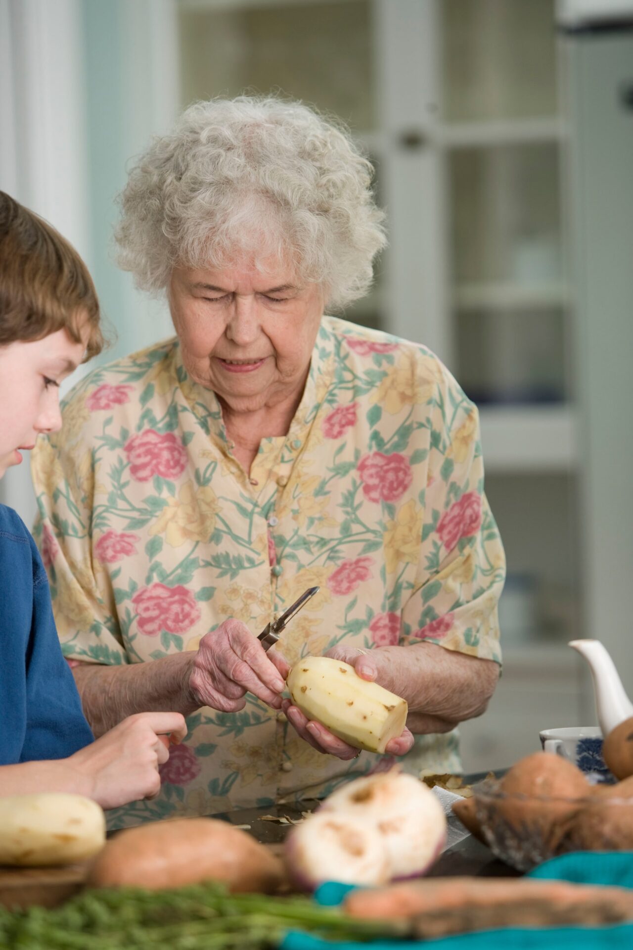 Grandmother peeling potatoes with her grandchild